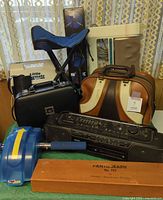 Group shot showing majority of items: stool, tripod sleeve, cooler, clarinet case, bowling bag, stereo, ab roller, pantograph box