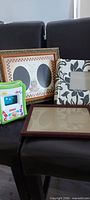 Group shot of assorted frames on chairs: double-oval wood frame, fabric vine frame, children’s green frame, brown wood frame