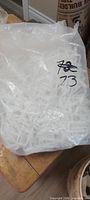 Large clear plastic bag filled with white plastic U clips