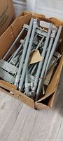 Cardboard box containing grey metal poles and connectors