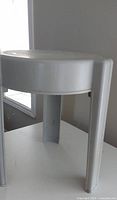 Full view of light gray plastic stool front and side