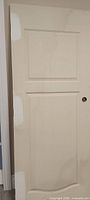 Front view of white two-panel door slab with knob hole