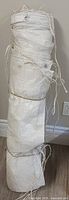 Rolled white tarp showing grommets and tie ropes