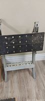 Front view of folding workbench showing black jaws with dog-holes and grey metal frame
