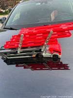 Overall view of Hot Wheels Mega Hauler on car hood showing extended red ramps and grey lower deck