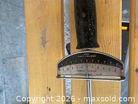 Close-up of torque wrench scale showing foot-pound and inch-pound markings and black handle