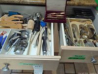 Open drawers showing variety of wooden utensils, measuring tools, knives in box