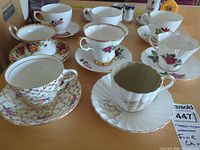 Overview of seven teacup and saucer sets on table