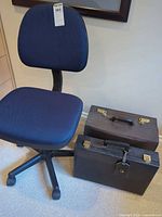 Blue office chair next to two hard-sided briefcases