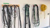 Multiple black, green and yellow extension cords hanging on wall
