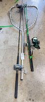 Three rods with attached reels and landing net laid out