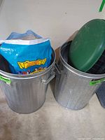 Two galvanized cans; seed bag inside one can; green lid visible