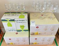 Four retail boxes of wine glasses, two Luminarc and two President’s Choice, with sample glasses displayed on top