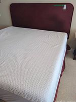 Full view of king bed showing headboard, mattress protector, box spring
