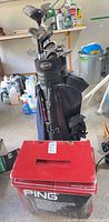 Full view of golf bag with clubs and adjacent Ping travel case box