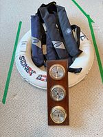 Group shot of lifebuoy, two PFDs and weather station