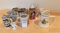 Group shot of all eleven steins and tankards on table