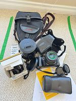Full lot layout showing camera body with lens attached, camera bag, hard lens case, boxed lens, manuals, flash and accessories