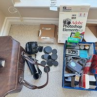 Overview of lot showing leather bag, lens caps, Adobe software box, film pack, accessories