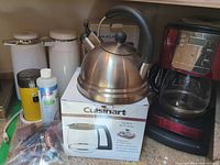 Whistling kettle on Cuisinart carafe box beside other kitchen items