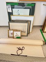 Group of framed artworks and rolled scroll standing together