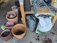 Terracotta and plastic pots, galvanized watering can, fertilizer bag, metal scroll brackets