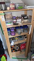 full shelving unit with jars, bins, tape rolls, paper roll
