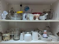 Overview of two cabinet shelves filled with assorted kitchenware and tableware