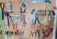 Full pegboard view showing majority of tools: hammers, hacksaws, clamps, pliers, screwdrivers, squares, and level