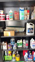 Full cabinet view showing multiple cans, jugs, aerosols and bottles