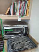Toaster oven on counter with cookbooks above and accessories in front