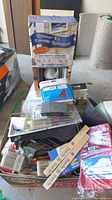 Lot overview showing restorer kit, paint brushes, mixing sticks, sanding pads, red roller cover pack and accessories