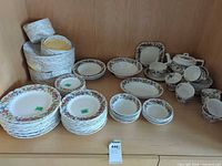 Full view of stacked dinner, salad, bread plates, bowls, serving pieces, teapot, cups and saucers