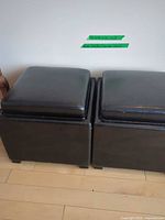 Two black faux leather storage stools side by side