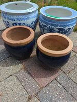 Two large blue & white ceramic fishbowls and two small dark blue terracotta pots grouped