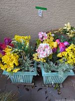 Two aqua plastic planters filled with mixed artificial flowers