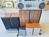 Front view of entire lot showing boombox, floorstanding speakers, bookshelf speakers, satellites, center speaker and Sony cubes