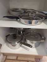 Two fry pans and lidded sauté pan on upper shelf