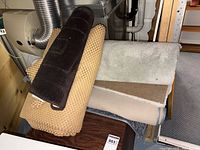 Stack of folded and rolled rugs in neutral colors beside HVAC unit