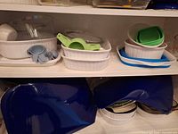 Cabinet shelves showing glass measuring cups, ceramic dishes, silicone strainers, blue bowls