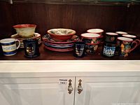 Shelf showing dinner plates, bowls and mugs