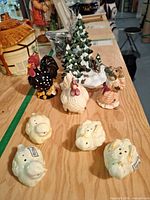 Group view of all ceramic figurines, chick shakers, village tree and some lamp posts