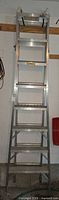 Full view of aluminum multi-way ladder standing vertically