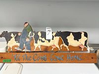 Full view of wooden sign showing cows, farmer and lettering