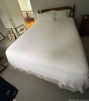 Full bed showing mattress with bedding, headboard, frame legs visible