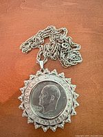Obverse of Eisenhower Bicentennial dollar coin in decorative starburst bezel with attached silver-tone rope chain