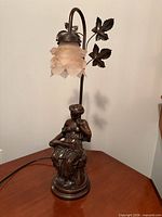 Full view of figural bronze table lamp showing base sculpture, leaf details and frosted glass shade