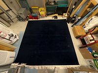 Full view of navy area rug with beige fringe in basement