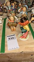 Front view of two figurines on display table within green tape