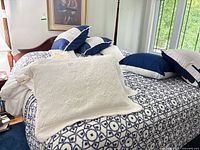 Bed showing quilted coverlet, shams and decorative pillows